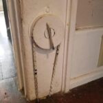 What is this dial with a chain that goes into the floor of this old house?